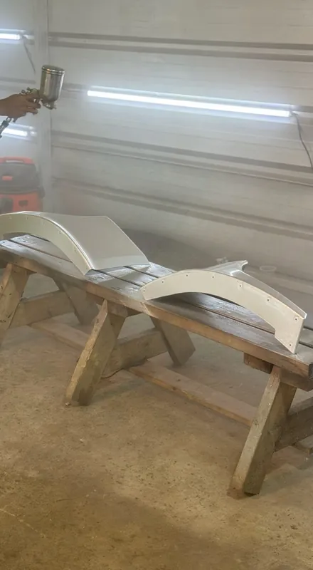 Bumper and wing panels on wooden stands in the spray booth