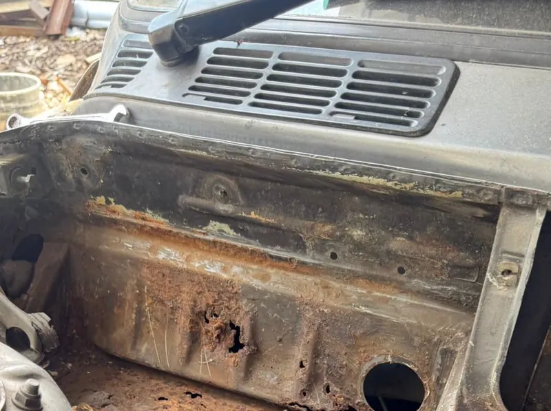 Rusted scuttle of the E30 with holes through it