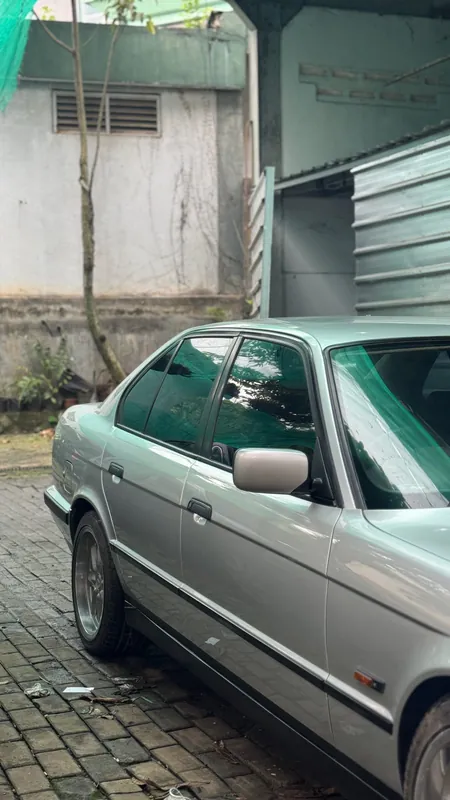 Silver BMW E34 side view in the yard