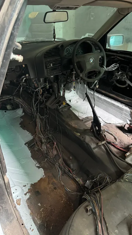 Stripped E36 cabin with the carpets out and the wiring loom hanging