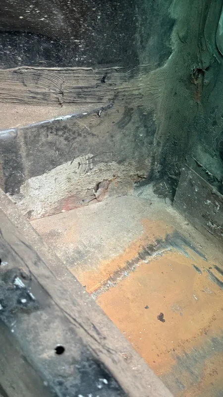 Rusted floor section in the footwell with the paint stripped