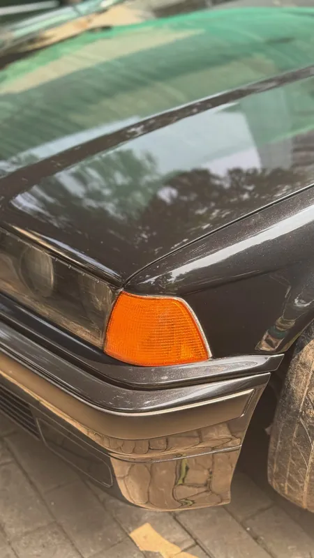 Front indicator and bumper corner of the black E36, glossy bonnet
