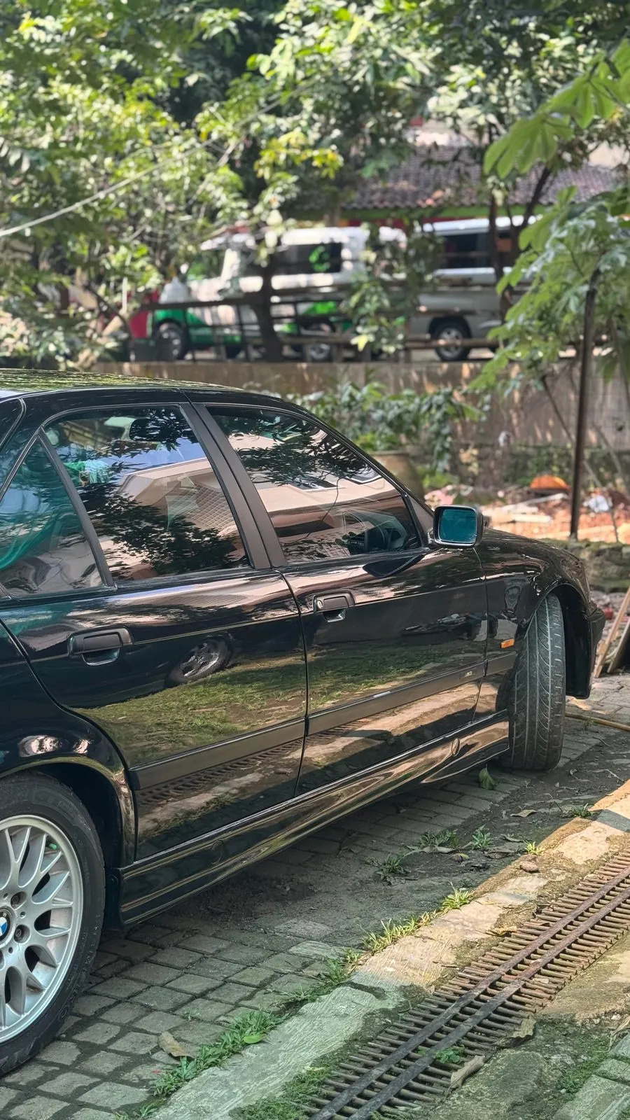 Black E36 side view, glossy paint, in the yard