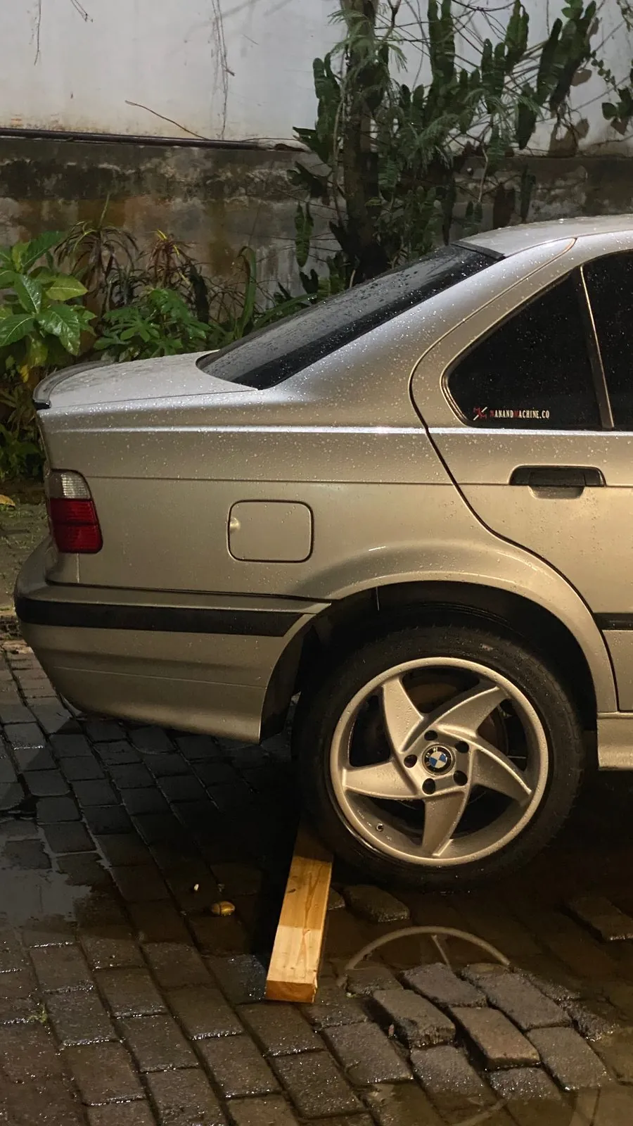 Silver E36 sedan on a wooden block with the rear wheel off
