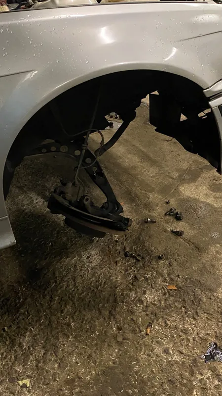 Front wheel arch of the silver E36 with the wheel off, strut and hub exposed