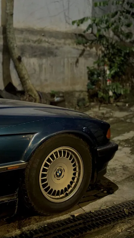 Front wing and BMW wheel of the dark blue E38 at night