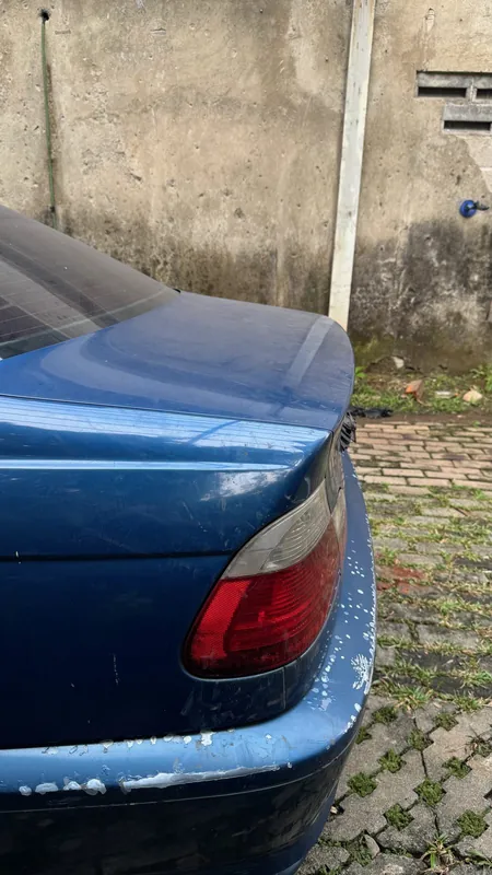 Boot lid edge and tail lamp of the blue coupe with chipped paint at the bumper