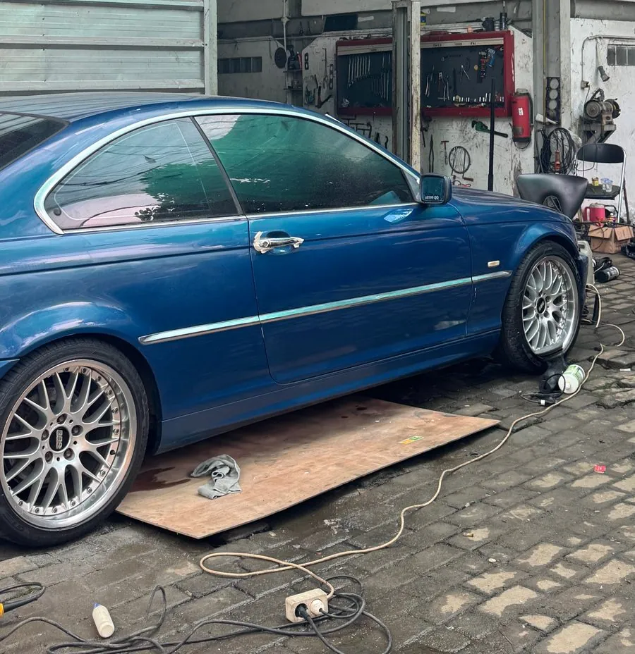Blue E46 coupe on mesh wheels in front of the lift bay