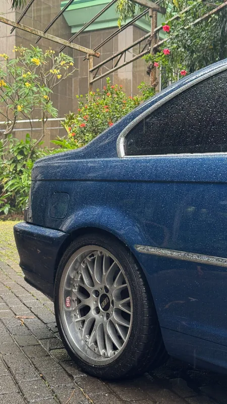 Rear quarter, side indicator and mesh wheel of the blue E46 coupe