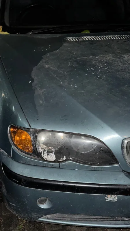 Bleached bonnet, cloudy headlight and scuffed bumper of the grey-blue E46