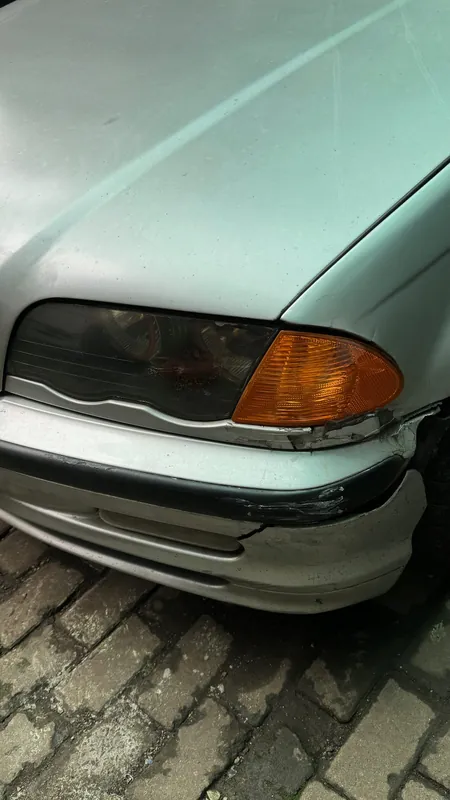 Silver BMW E46 bonnet and front bumper corner with a crease