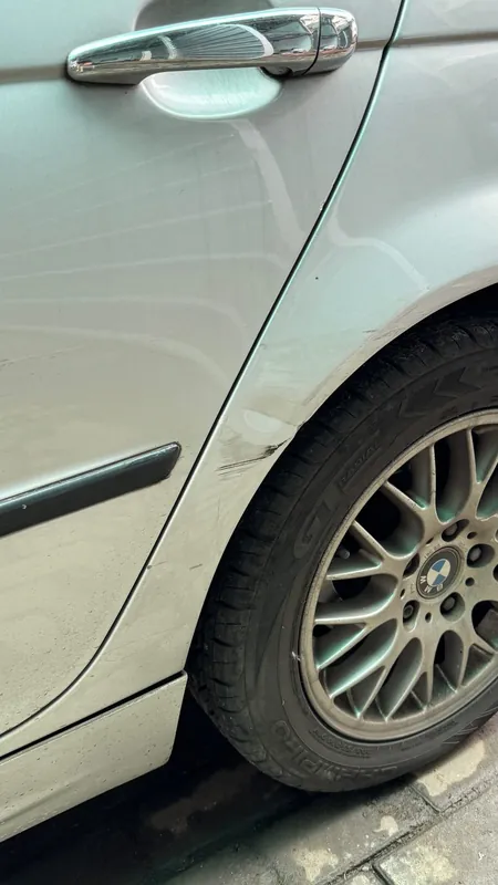 Rear wheel arch of the silver E46 with a dent and a scrape