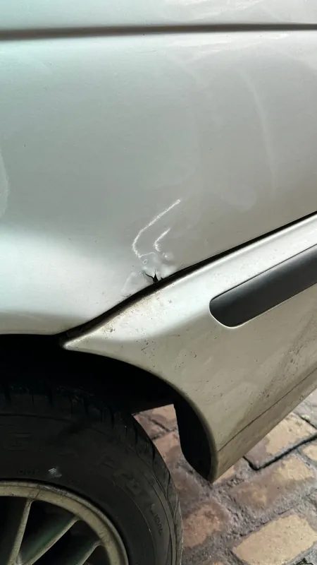 Rear wheel arch lip with a deep dent and cracked paint