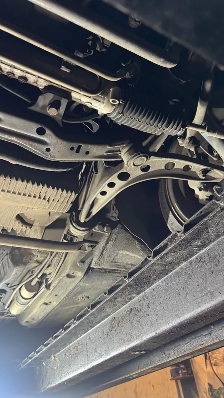 Underside of an older BMW on a lift: steering rack, front lower arm and sill