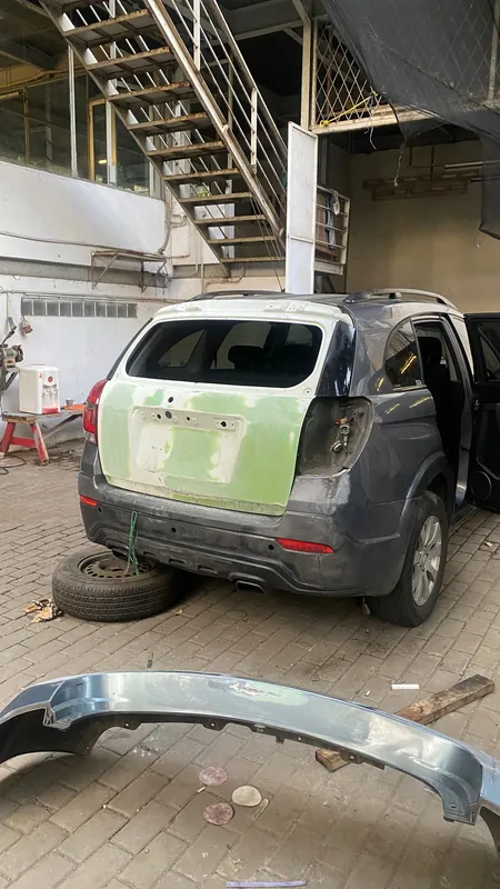 Dark grey Chevrolet Captiva with the tailgate and rear in light-green primer, bumper off