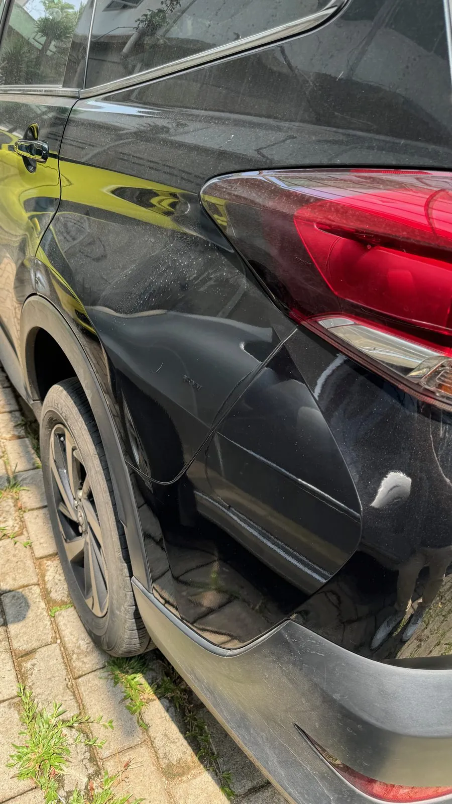 Dented rear quarter panel and tail light of a dark SUV