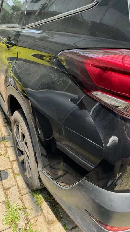 Dented rear quarter panel and tail light of a dark SUV