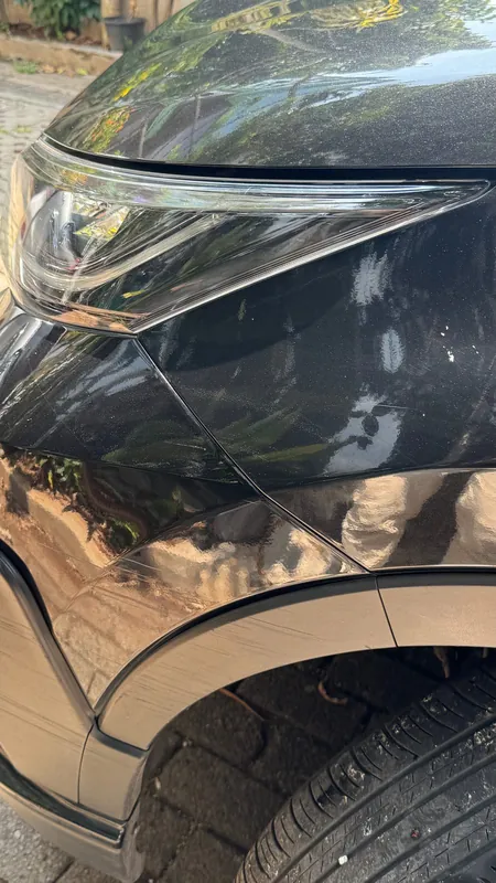 Front wing, headlight and wheel arch of the dark SUV with scuffs