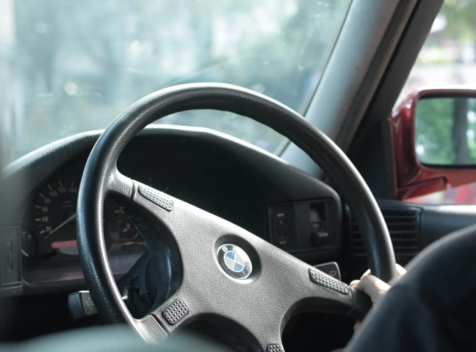 BMW E34 steering wheel seen from the cabin, a hand on the rim