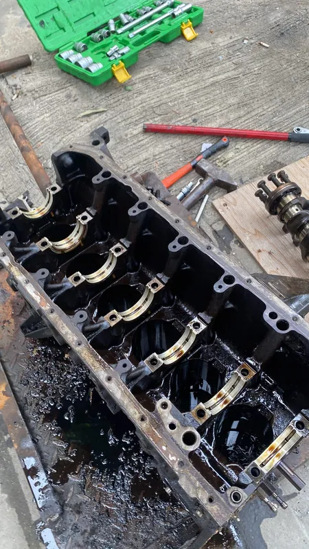 Open cylinder block with main bearing shells, crankshaft beside it