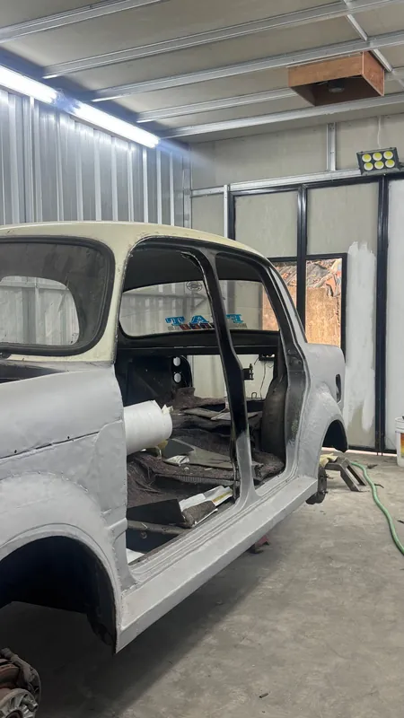 Fiat 1100 shell in grey primer, doors open, in the spray booth