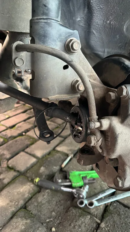 Front hub, brake caliper and ABS lead with the wheel removed, spanners below