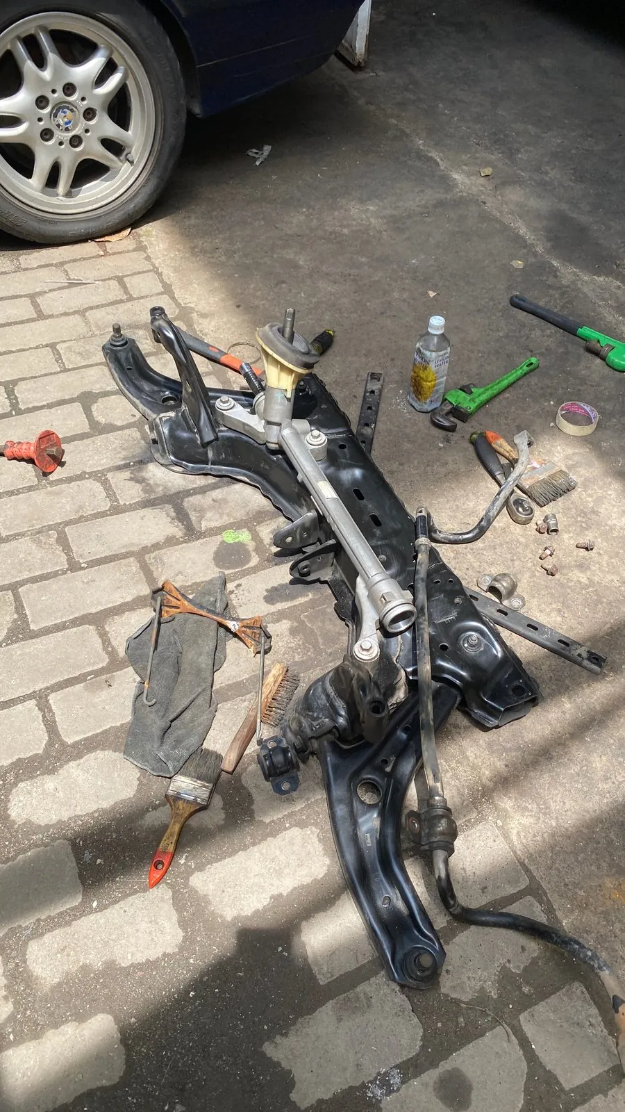 Front subframe with the steering rack and control arms laid out on the paving