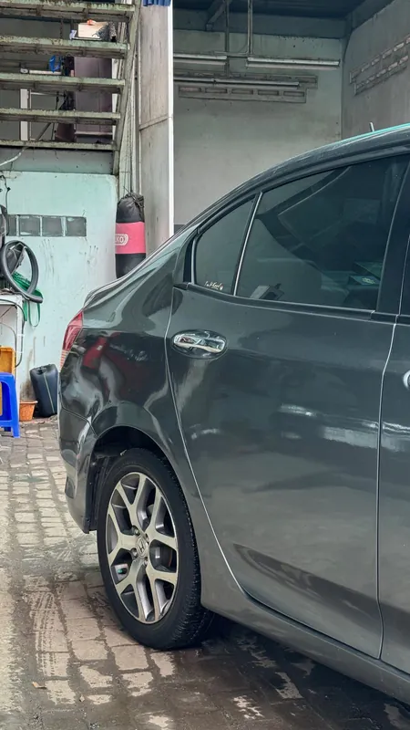 Side of the grey Honda City with a dent in the rear door and rear wing