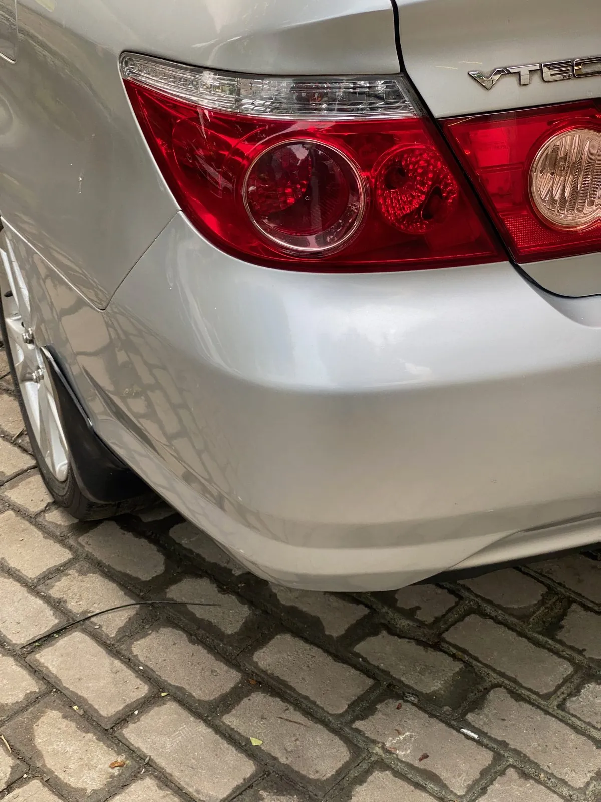 Rear lamp, VTEC badge and scuffed bumper corner of a silver Honda City