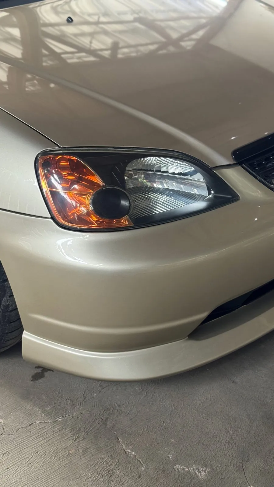 Front bumper corner and headlight of the gold Honda Civic