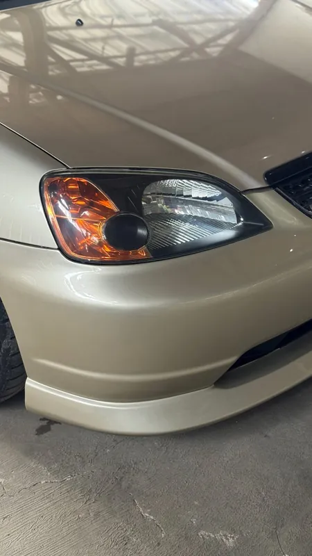 Front bumper corner and headlight of the gold Honda Civic