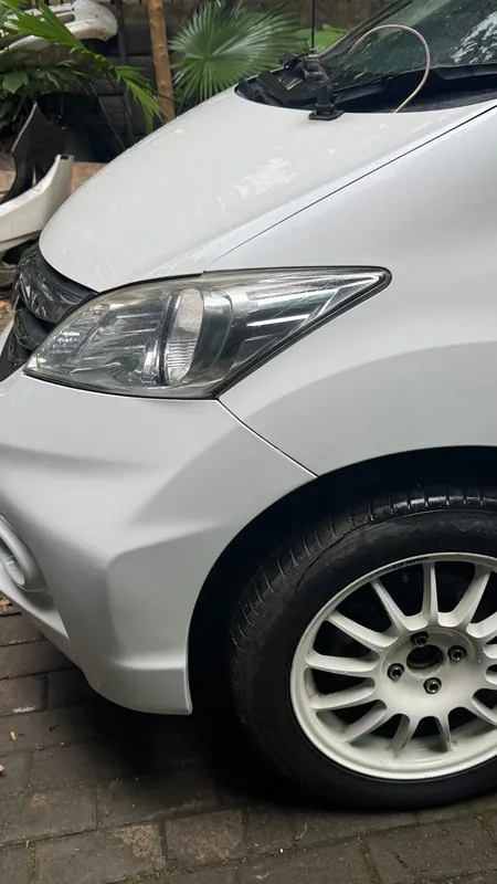 Front wing, headlight and wheel of the white Honda Freed