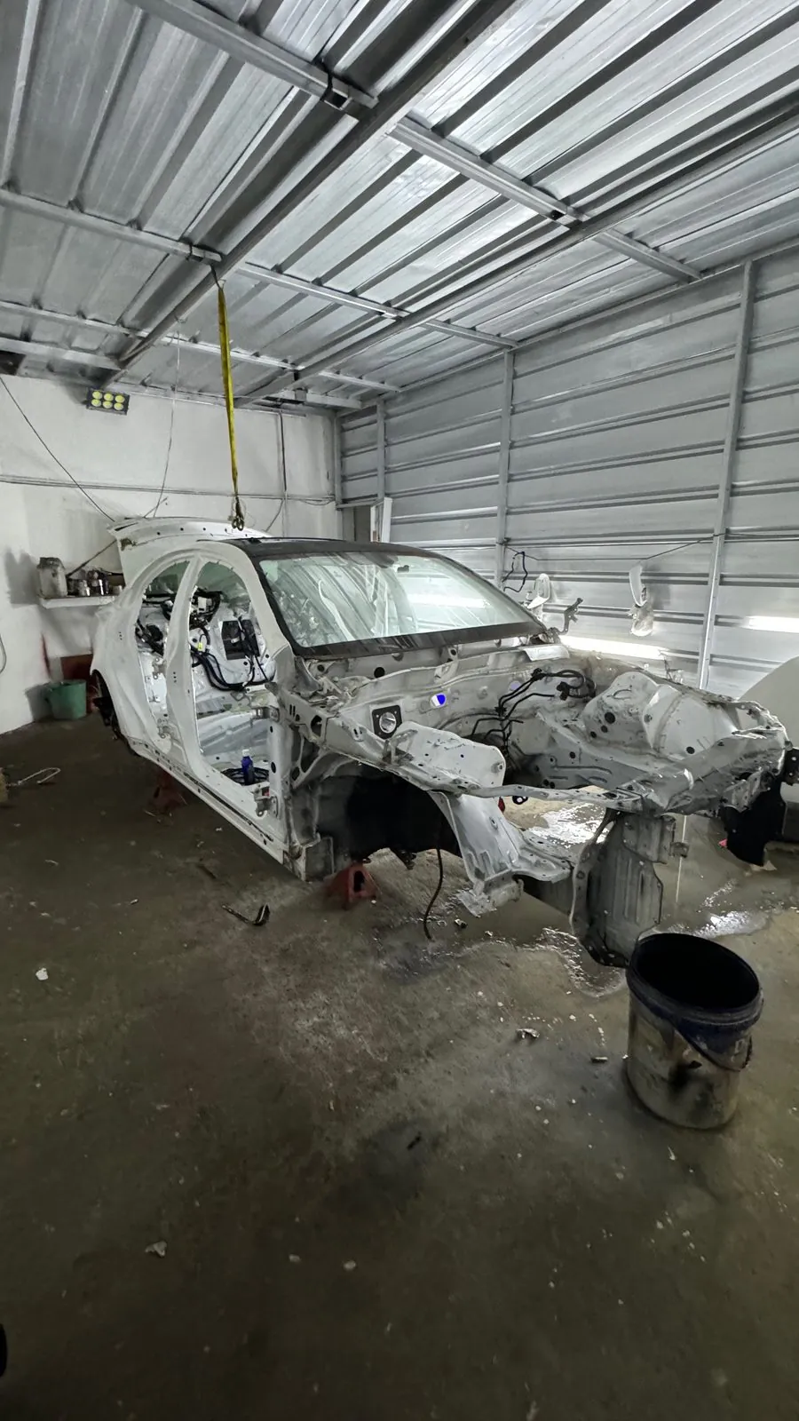 Wide view of the white shell in the spray booth on stands