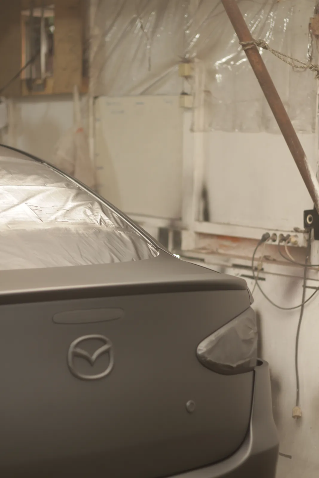 Mazda badge on a boot lid in grey primer