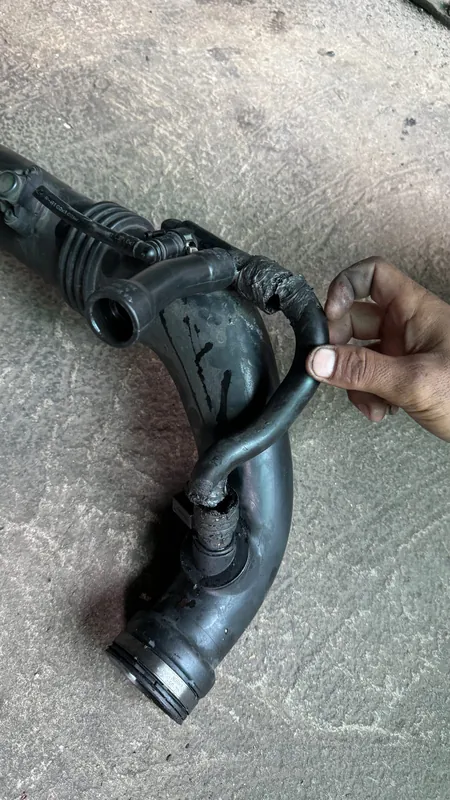 Hand holding a removed rubber air intake hose
