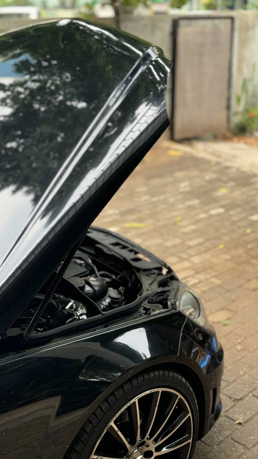 Black Mercedes saloon with the bonnet raised in the yard