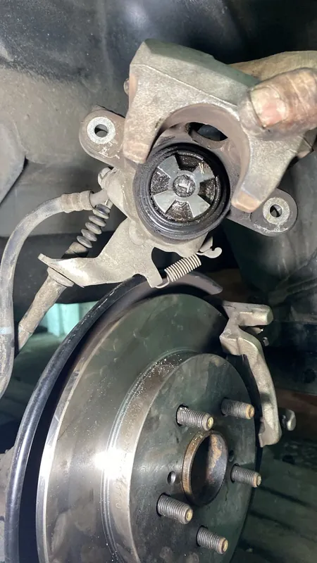 Rear brake caliper and disc with the wheel off, hub studs visible