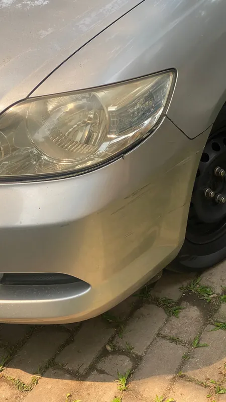 Silver sedan front corner with a cracked, scuffed bumper