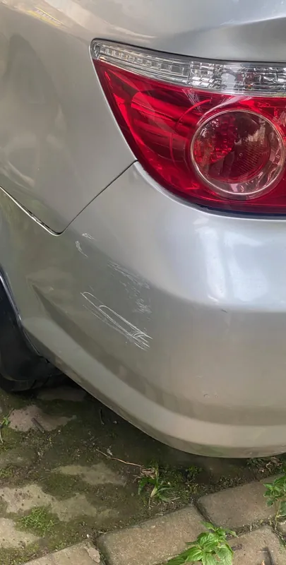 Rear quarter and tail light of the silver sedan with a creased bumper corner