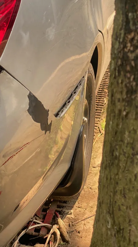 Rear wing of the silver sedan with a paint chip and a dent by the arch