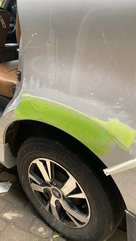 Silver Toyota Avanza front wing in light-green primer above the wheel