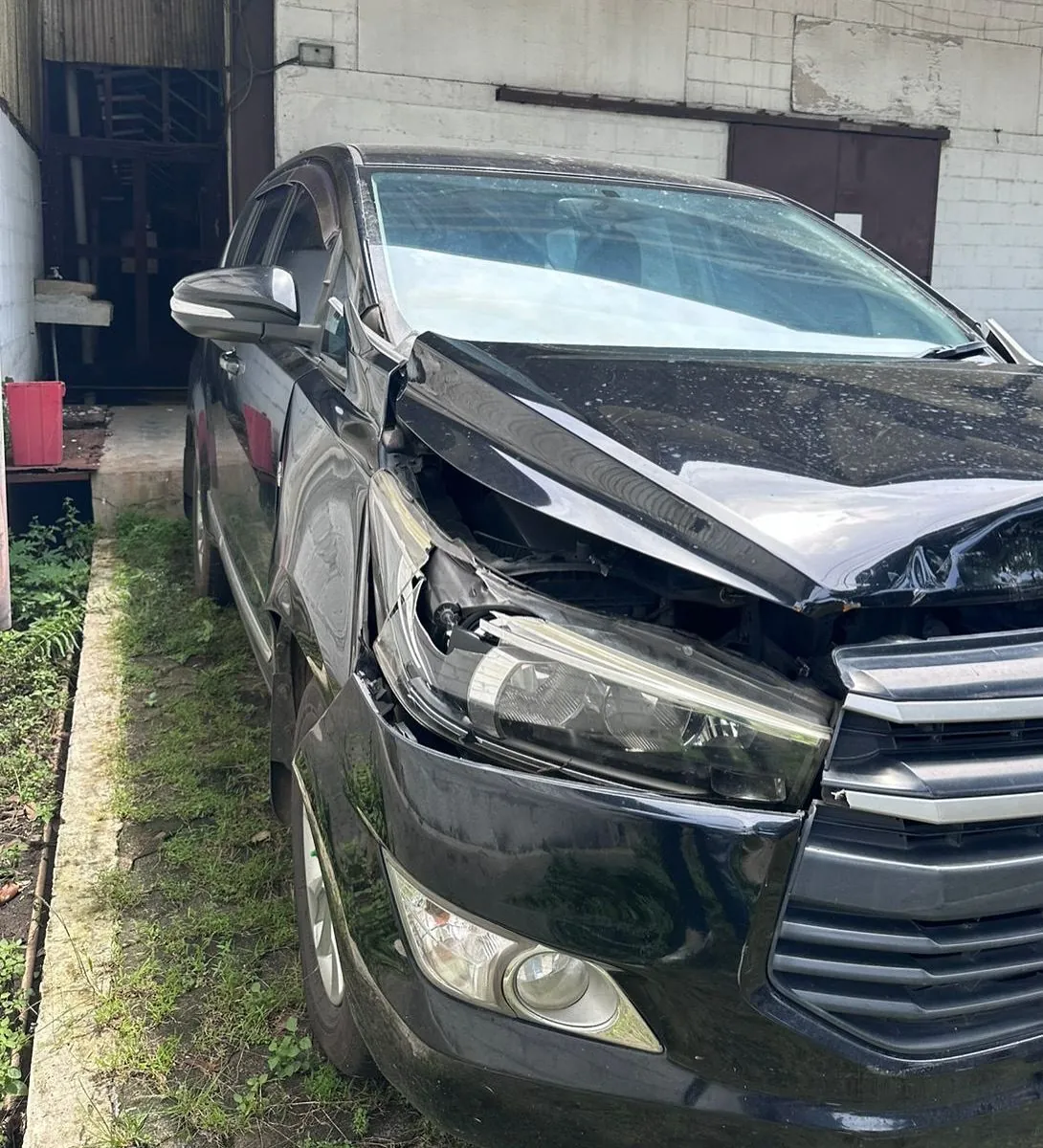 Black Toyota Innova with a crushed front, bent bonnet and broken headlight