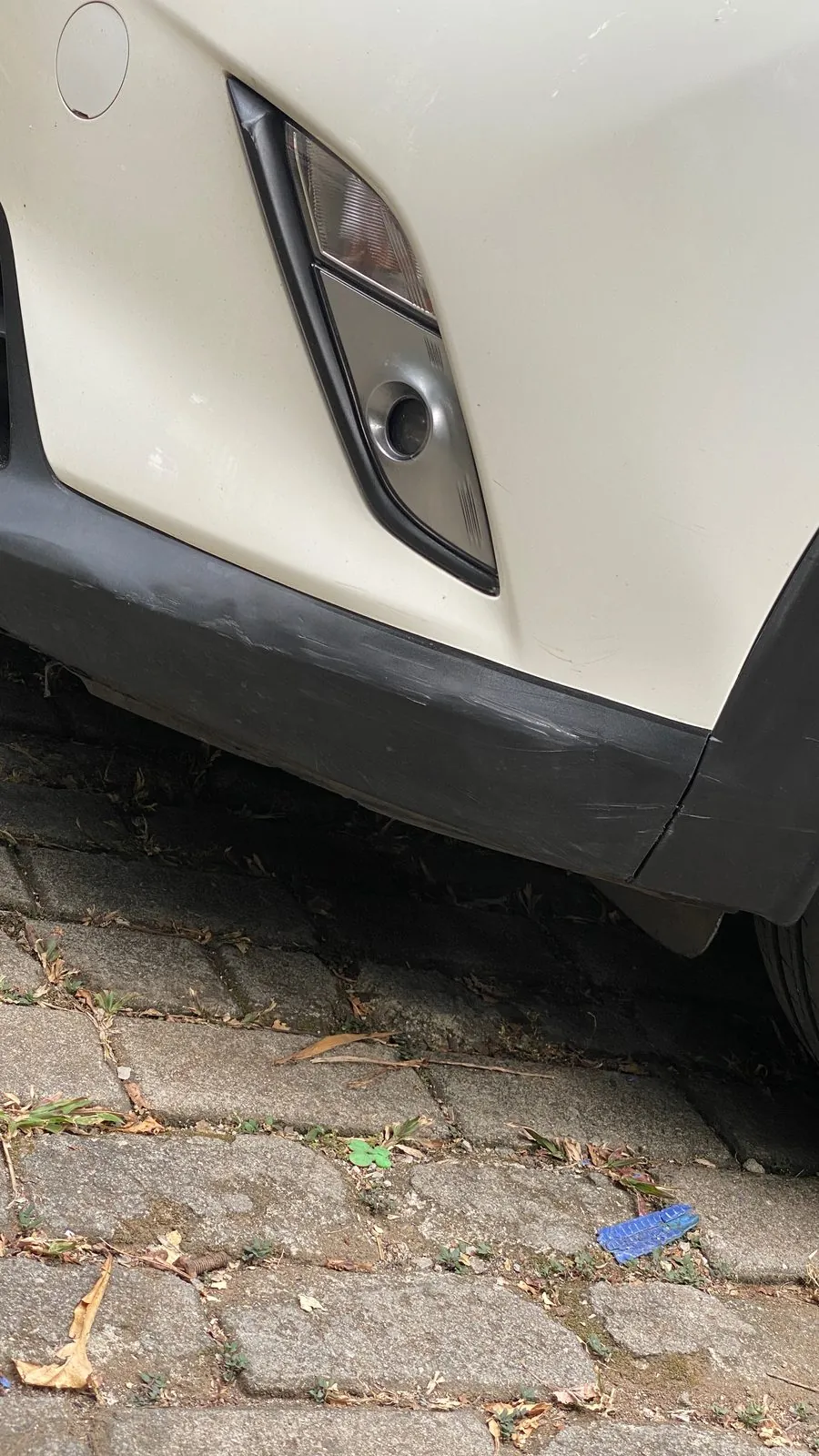 Bumper corner and fog lamp surround of a white SUV with a crease