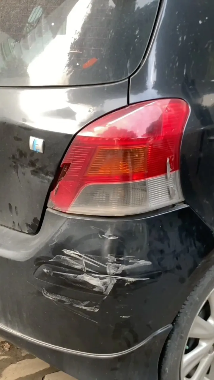Scratched and dented rear bumper of a black Toyota Yaris